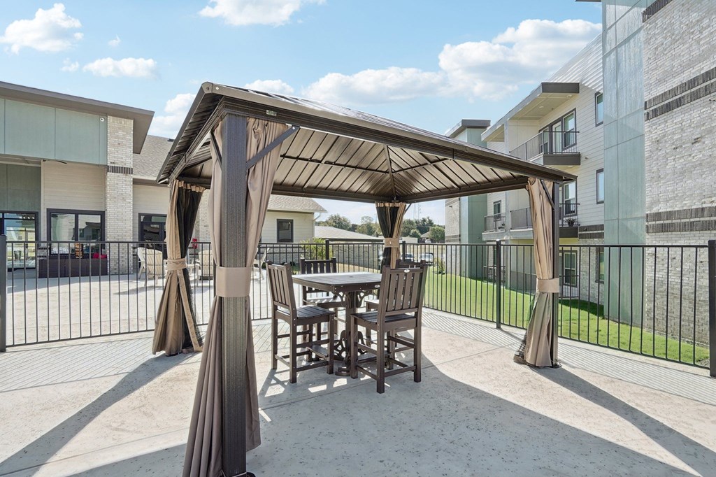 a patio with a table and chairs under a gazebo