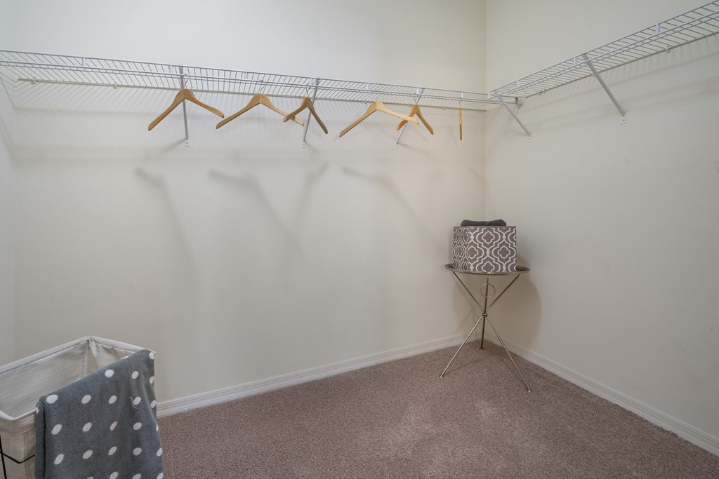 a walk in closet with white walls and carpet