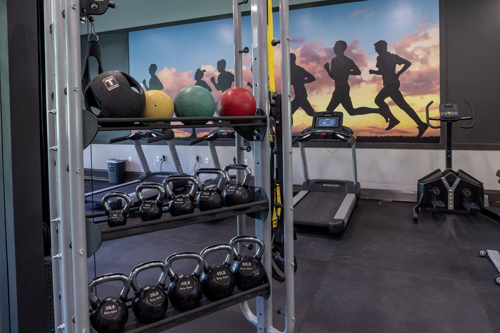 a gym with weights and a mural of runners on the wall