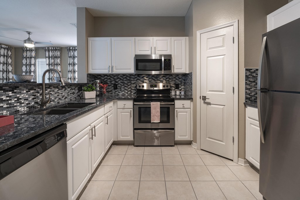 a kitchen with white cabinets and black countertops