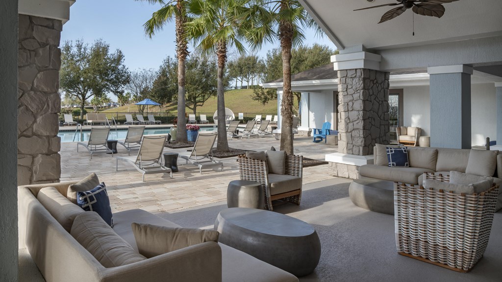 a patio with couches and chairs and a pool in the background