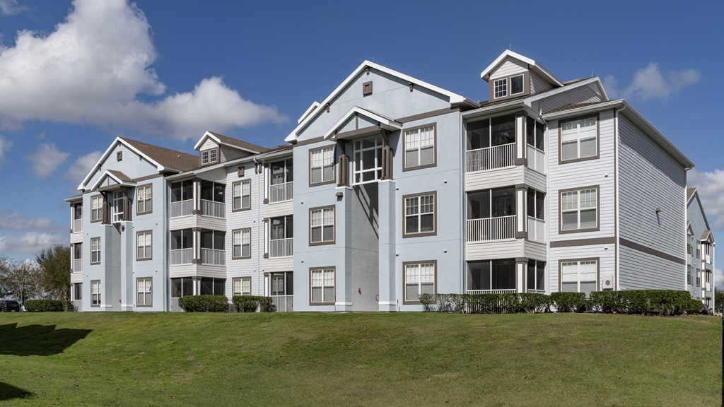 an apartment building on a hill with a grassy area in front of it