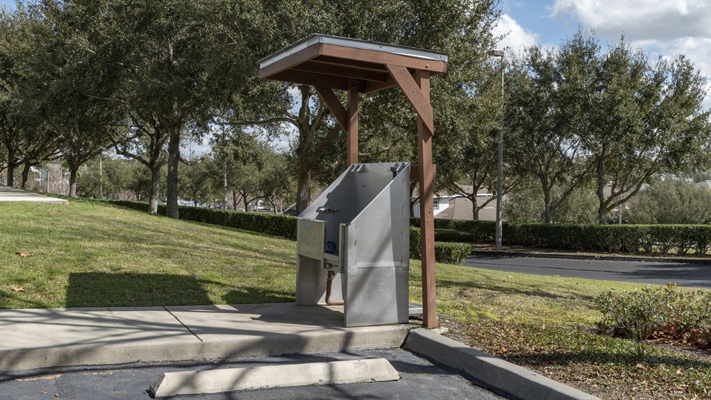 a parking meter in a park with trees in the background