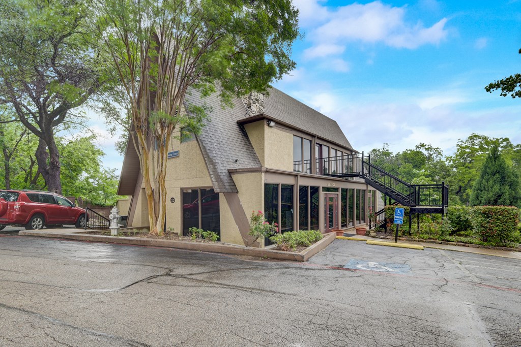 the front of a building with a parking lot and a tree