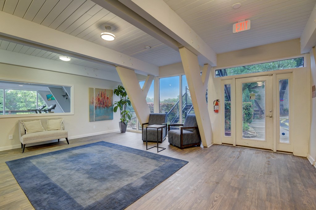 a living room with a blue rug and chairs and a large window