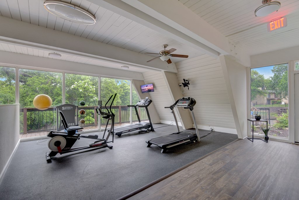 two treadmills and other exercise equipment in a room with large windows