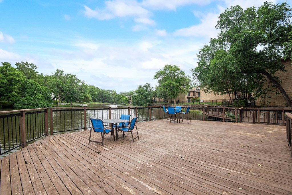 a deck with a table and chairs on it overlooking a body of water