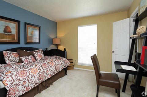 a bedroom with a bed and a desk with a chair