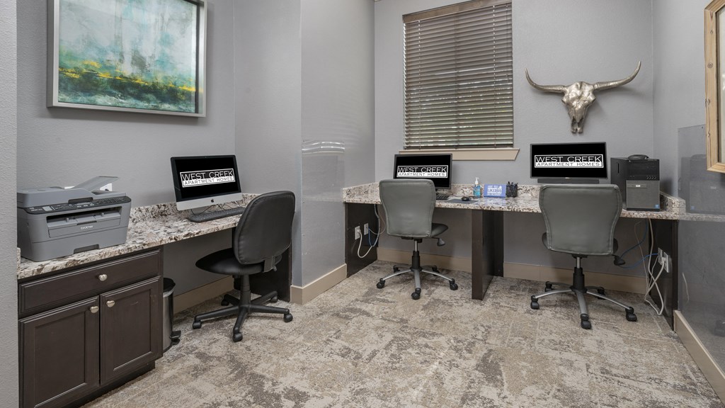 two desks with computers and chairs in a room with a printer and a window