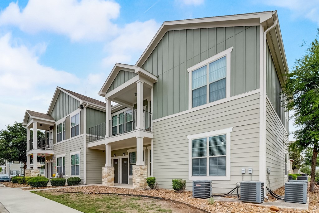 a row of houses with green siding and a sidewalk