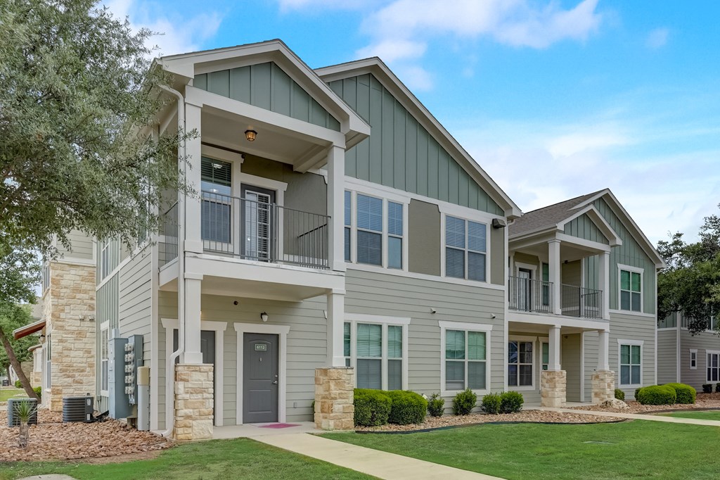 an apartment building with gray siding and a sidewalk