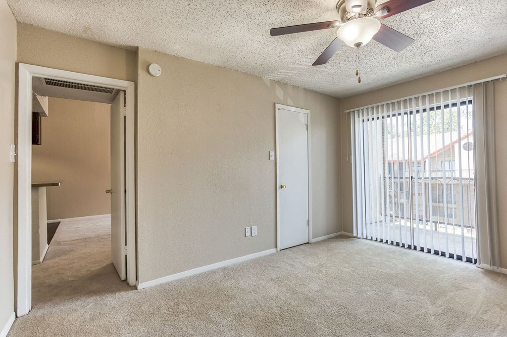 an empty living room with a ceiling fan and a window