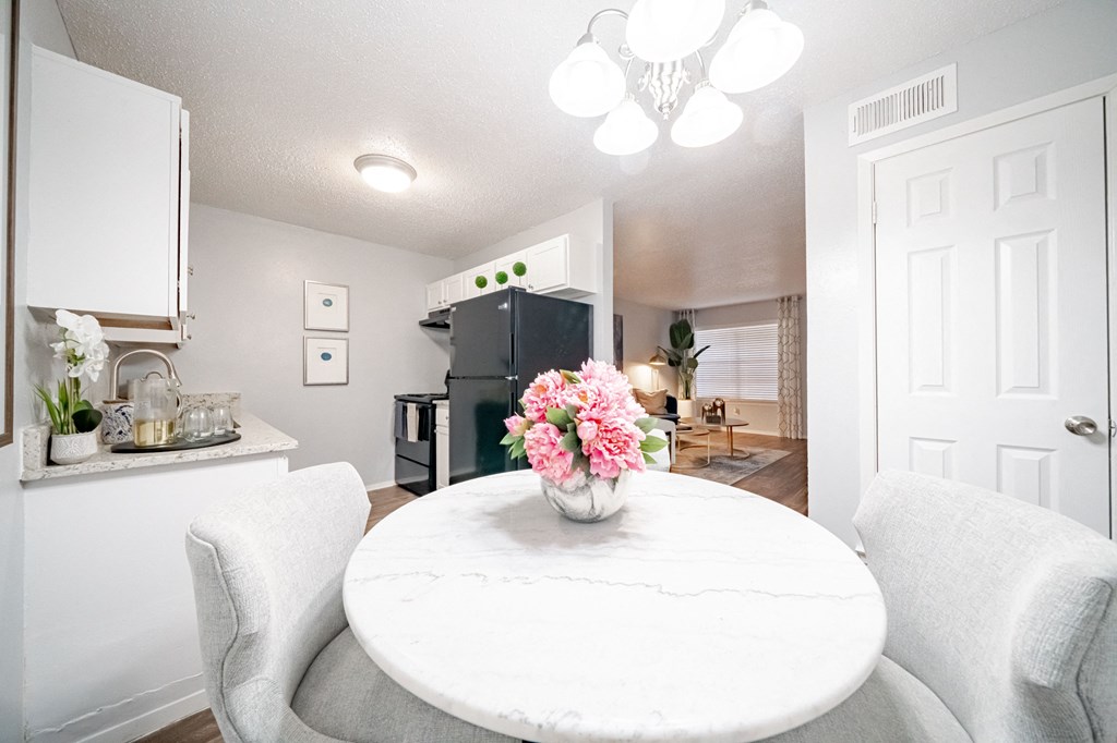 a kitchen and dining room with white chairs and a table with flowers