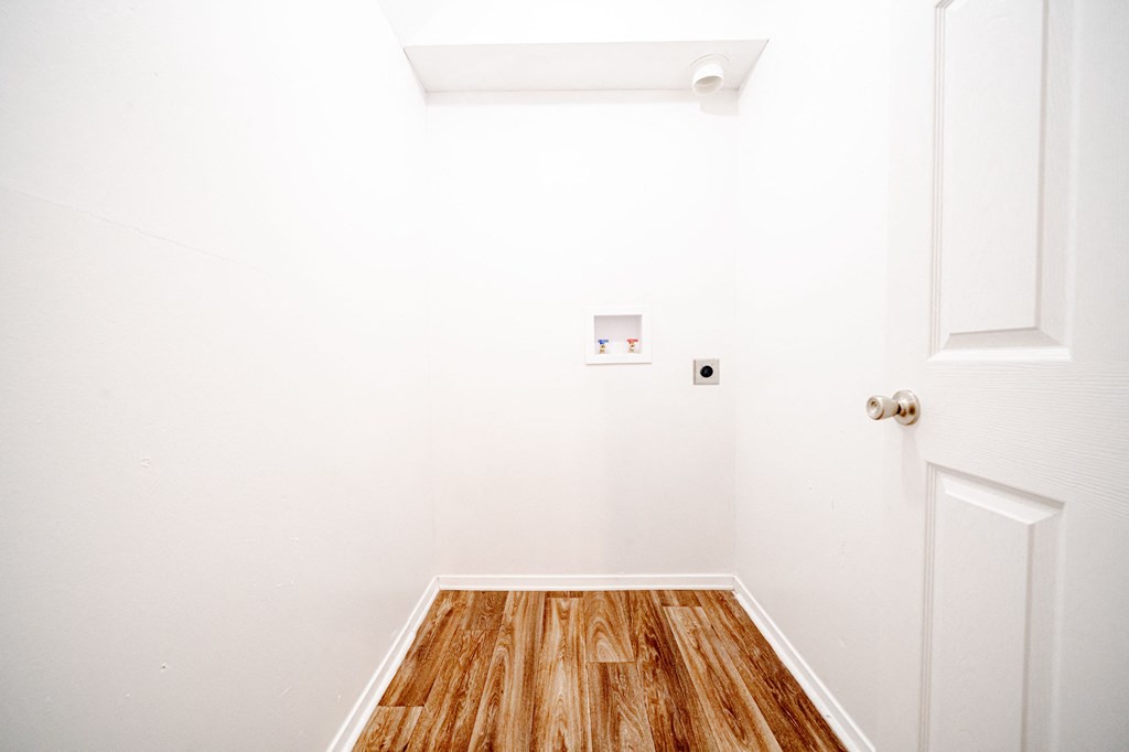 a room with white walls and wood floors and a white door