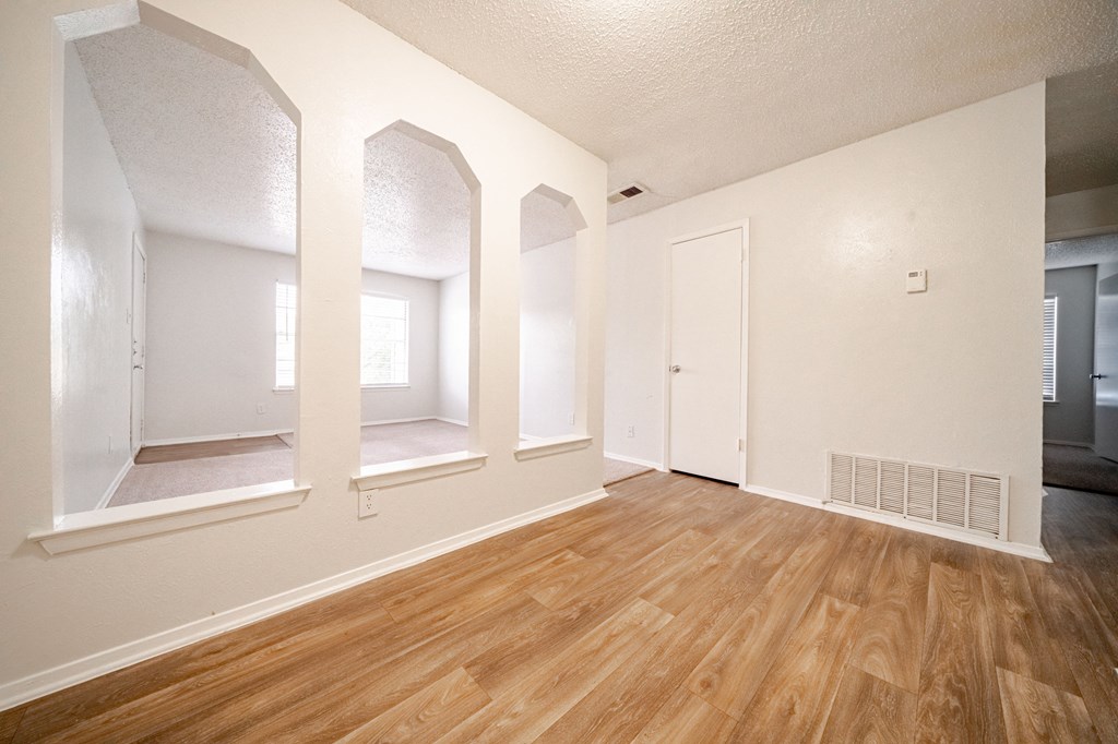 the living room and dining room of an apartment with wood floors and white walls