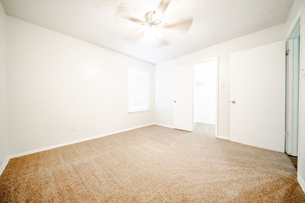 an empty living room with a ceiling fan and white walls