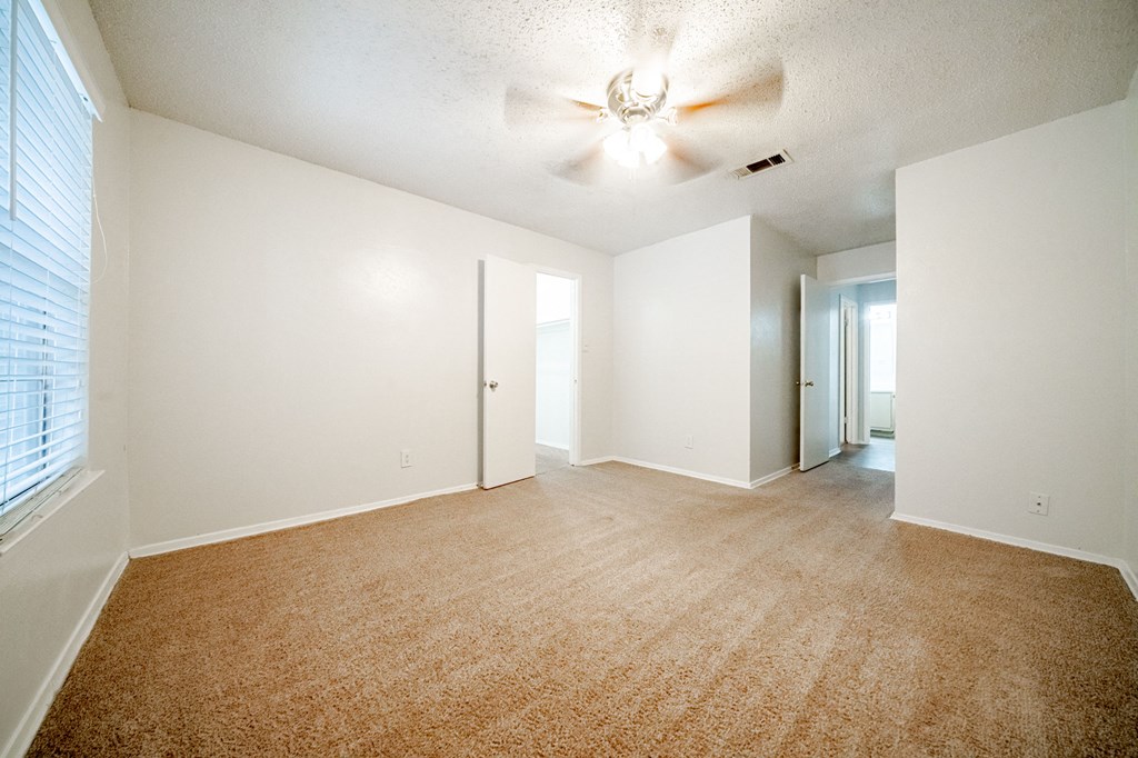 an empty living room with white walls and a ceiling fan