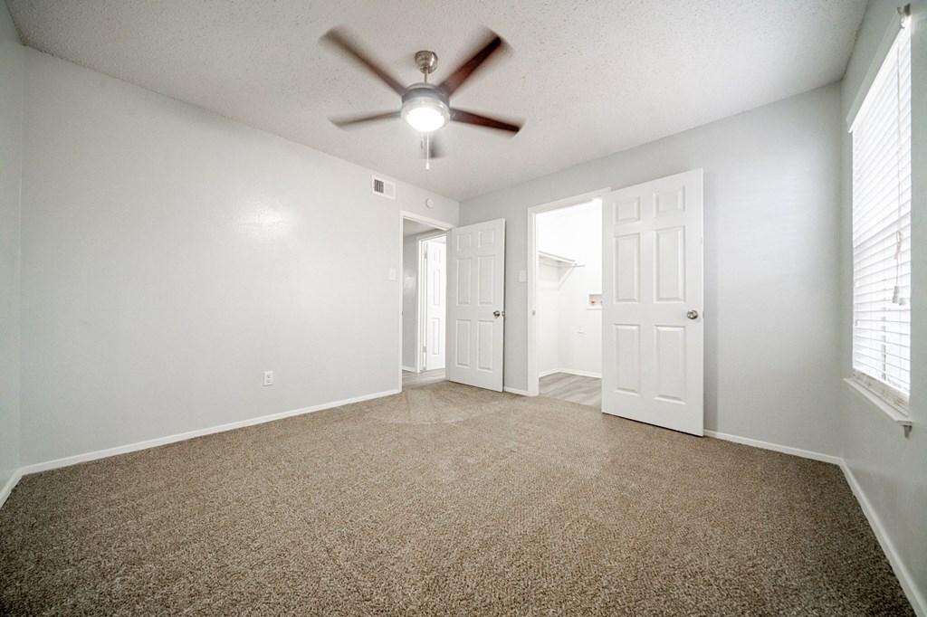 an empty living room with a ceiling fan and white walls