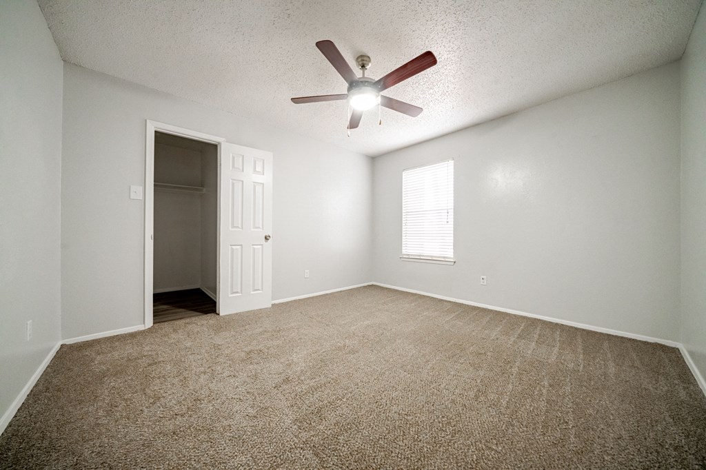 an empty living room with a ceiling fan