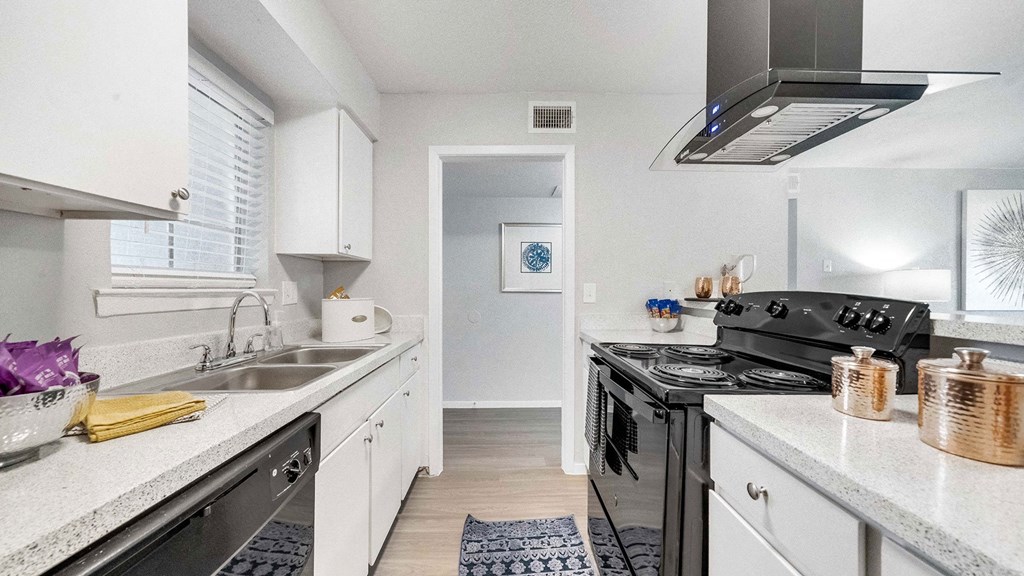 a kitchen with white cabinets and a black stove and a sink