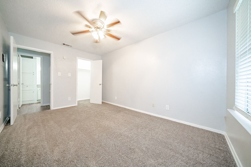 an empty living room with a ceiling fan
