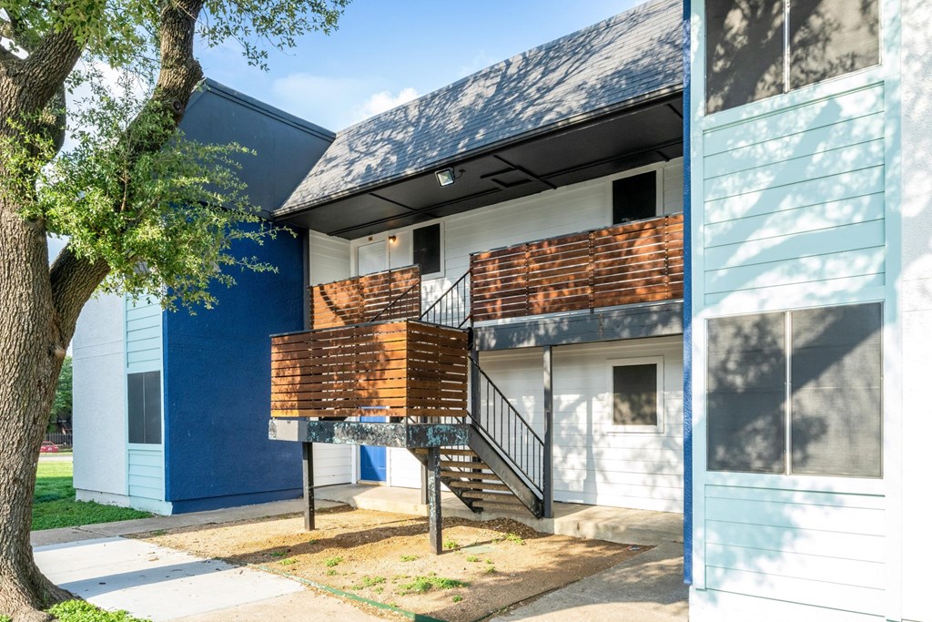 a building with a balcony and a tree in front of it