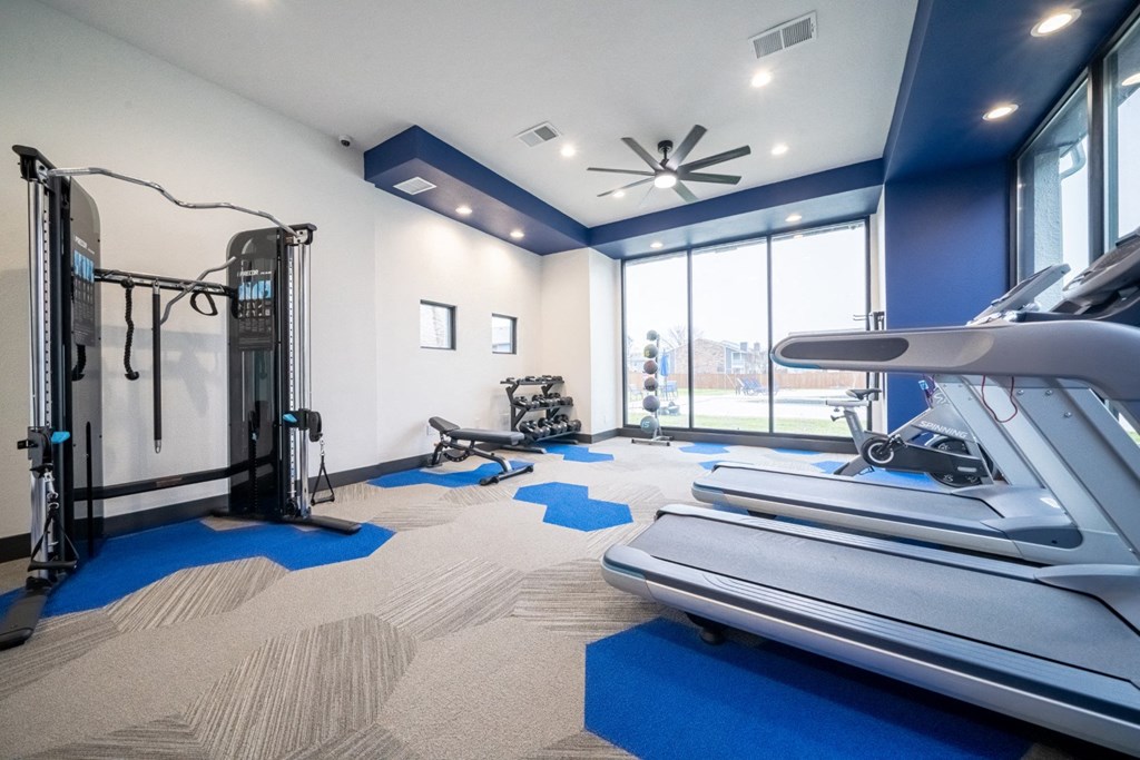 the gym with treadmills and weights at the district at highland village apartments