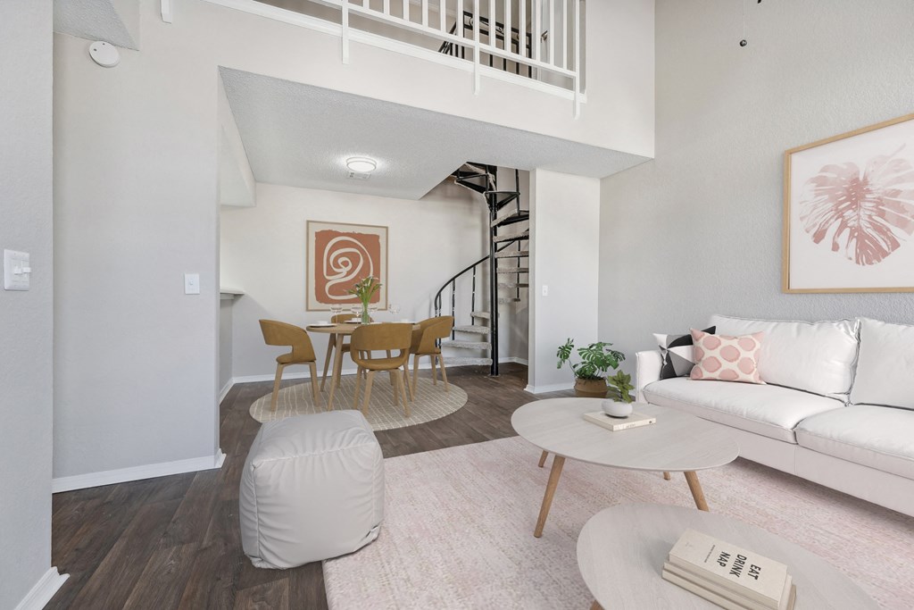 a living room with a white couch and a table and a spiral staircase
