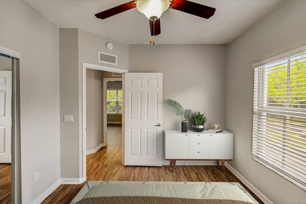 an empty bedroom with a ceiling fan and a white dresser