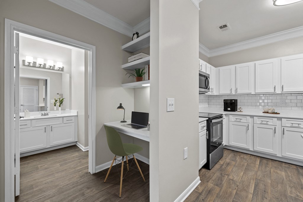 a kitchen with white cabinets and a desk with a laptop