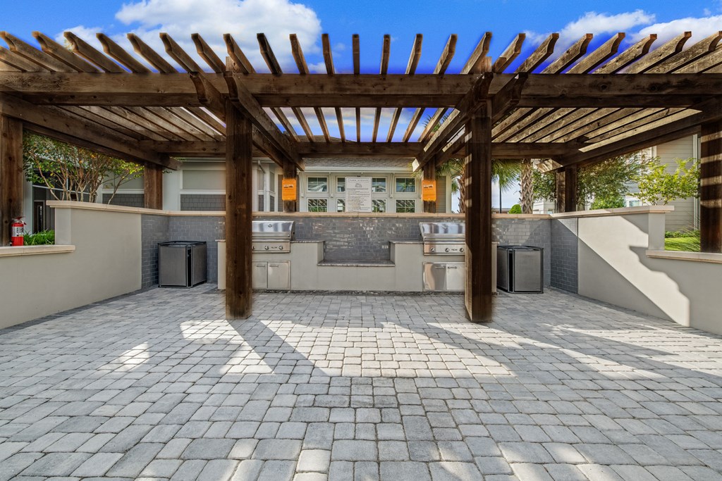 a patio with a pergola and a kitchen in the background
