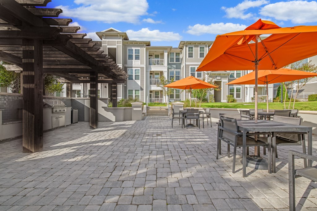 a patio with tables and chairs and orange umbrellas