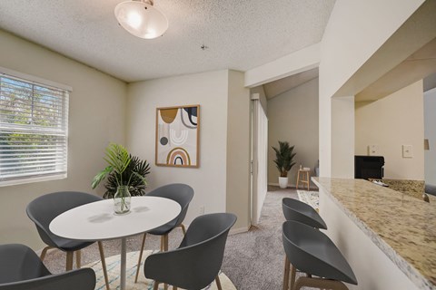 a dining area with a table and chairs and a kitchen with a counter and a