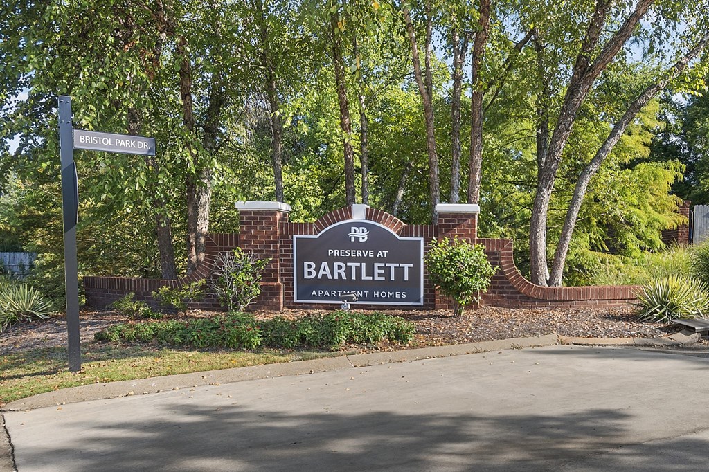 a sign in front of a brick wall with trees