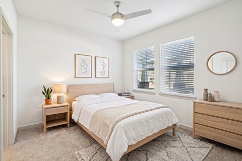 A bedroom with a bed, nightstand, and a ceiling fan.