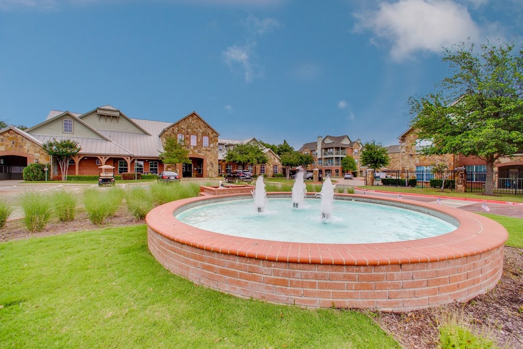 a fountain in the middle of a park in front of a house
