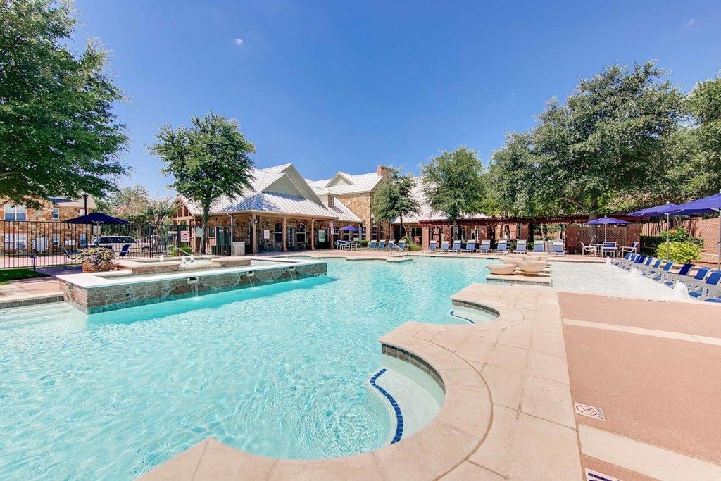 a large pool with chairs and umbrellas at the resort on a sunny day