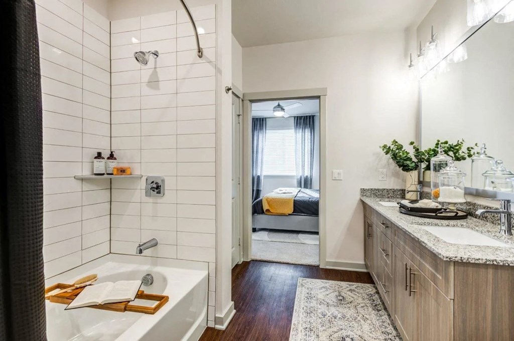 a bathroom with a tub and a sink and a door to a bedroom