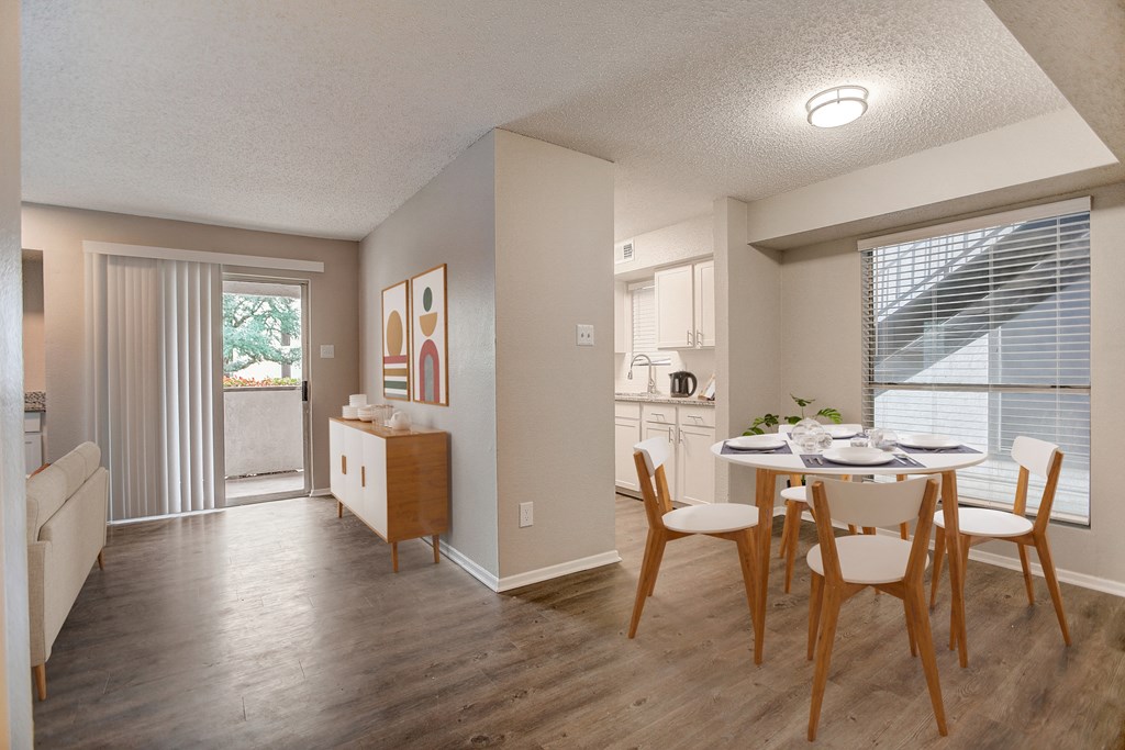 the living room and dining room of an apartment with a table and chairs