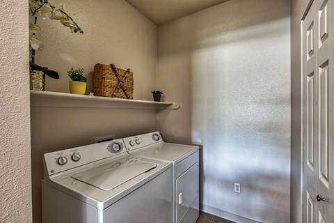 A small kitchen with a stove top oven and a wall-mounted shelf with a plant and a basket on it.