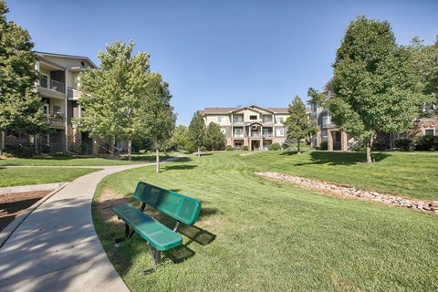A park with a bench and apartment buildings in the background.