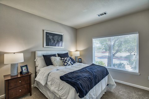 A bedroom with a large bed and a window with blinds.