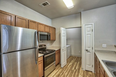 A kitchen with a stainless steel refrigerator, microwave, oven, and wooden cabinets.