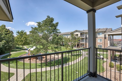 A balcony overlooks a playground and apartment buildings.