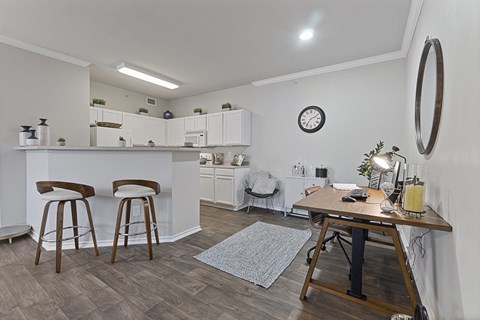A kitchen with white cabinets and a bar area with stools.