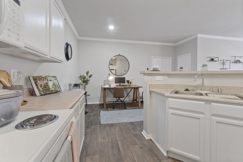 A kitchen with white cabinets and a wooden floor.