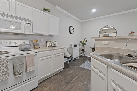 A kitchen with white cabinets and a wooden floor.