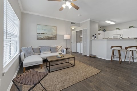 A living room with a white couch and a painting on the wall.