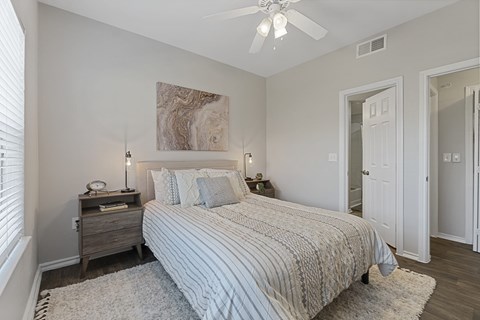 A bedroom with a bed, nightstand, and a ceiling fan.