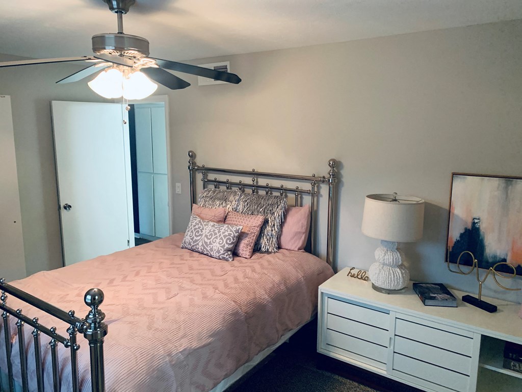 a pink and white bedroom with a bed and a ceiling fan